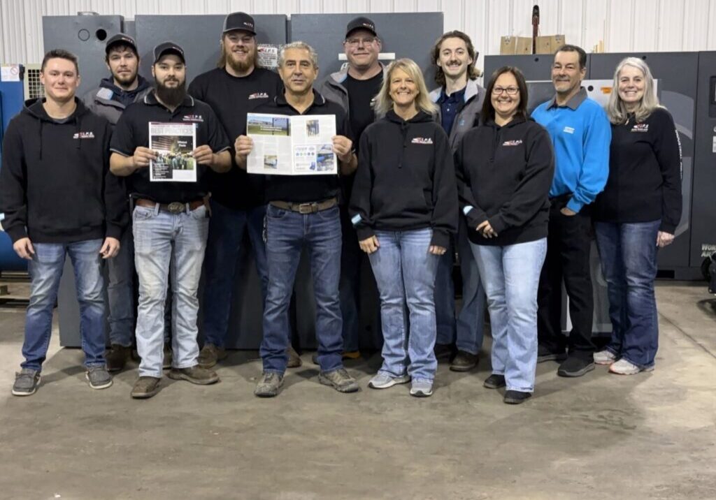 ips-group-photo-with-magazine 11 of Industrial Pneumatic Systems' employees standing in a group with two men holding up copies of the Compressed Air Best Practices magazine